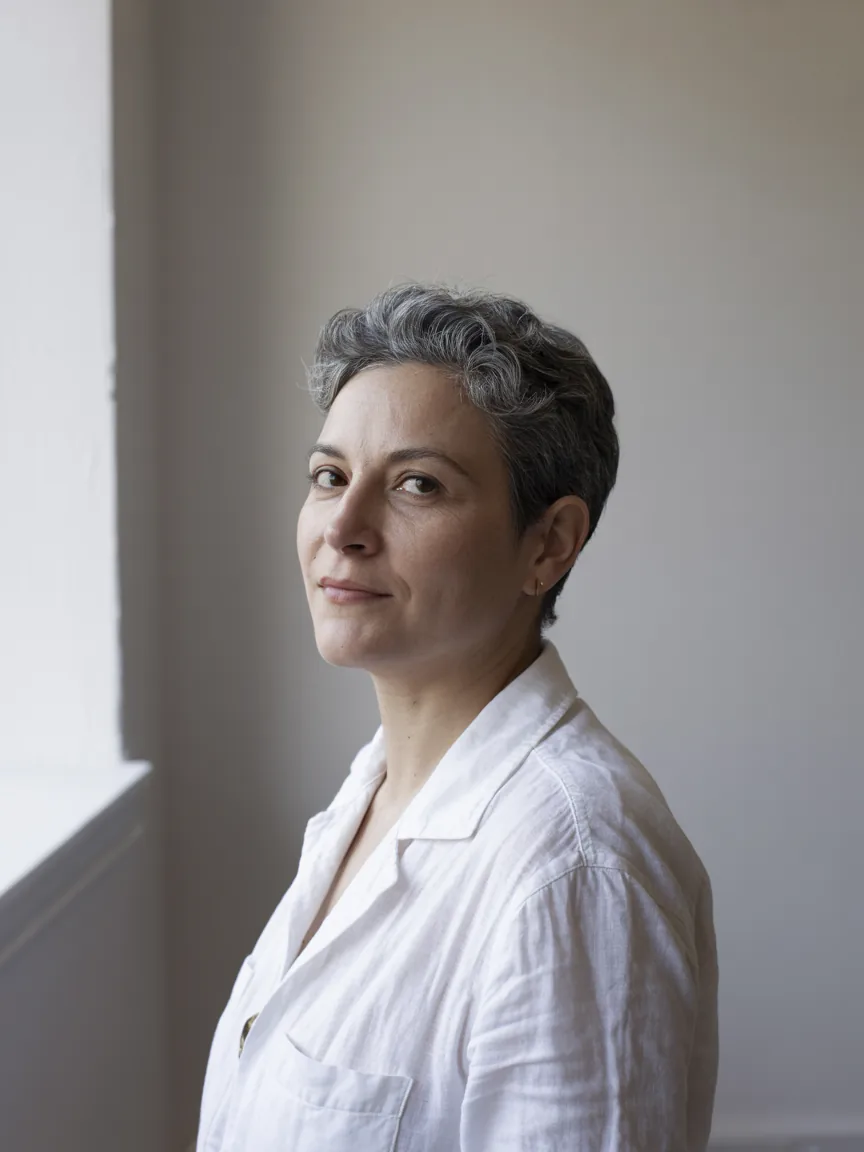 Júlia Salgado, psicóloga, retrato em camisa branca de linho diante de parede branca